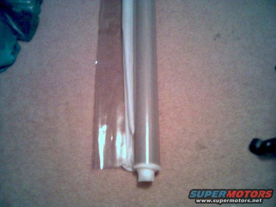 rolled up plastic sheeting next to a white tube on a carpeted surface