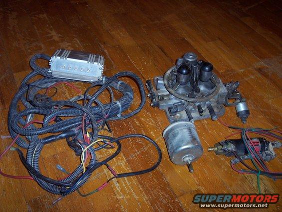 Carburetor, electronic control module, and wiring harness laid out on a wooden floor