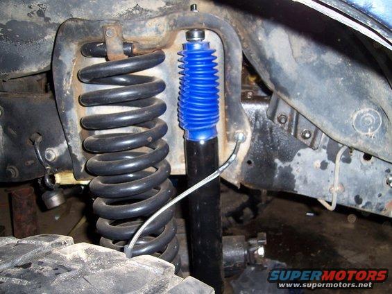 Black coil spring and blue-booted shock absorber assembly on a vehicle's suspension