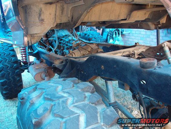 Vehicle frame with exposed drivetrain, large tires, and suspension components. Some rust visible