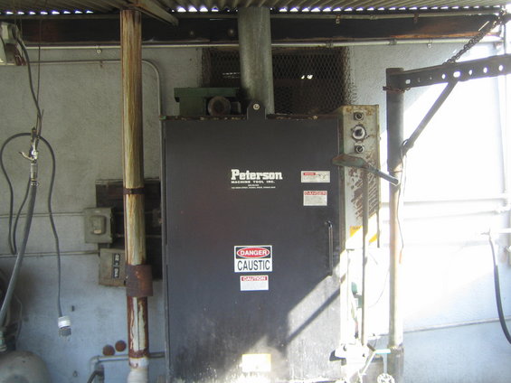 Black industrial cabinet with 'Peterson MACHINE TOOL, INC.' logo and 'DANGER CAUSTIC' labels