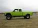 1986 Ford Ranger - Lifted 1986 Ford Ranger pickup truck in lime green parked on a sandy beach with overcast sky.