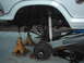 1978 Ford Bronco - Undercarriage view of a white vehicle, lifted on jack stands, with visible suspension components like coil springs and shocks.