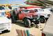 1989 Ford F-350 - A vintage red Dodge Power Wagon is parked next to other vehicles under a canopy.