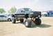 1989 Ford F-350 - Modified black Ford pickup truck with extensive lift kit and oversized tires on display.
