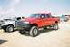 1989 Ford F-350 - A red crew cab pickup truck is parked outside with another truck beside it under a bright sky.