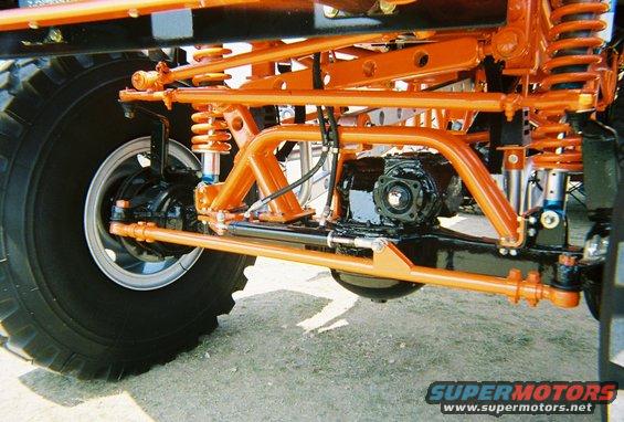 Close-up of orange suspension components and black differential on a large off-road vehicle