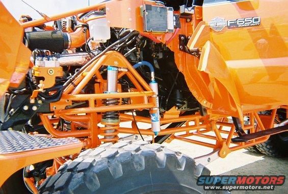 Orange Ford F-650 Super Duty front suspension with large tire and custom roll cage