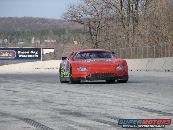 Red race car with number 80 on the side, on a track. Billboard in background says Green Bay, Wisconsin