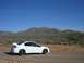 1996 Ford Probe - A white sedan with a spoiler is parked on a dirt road in a desert landscape.