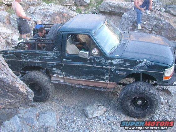 Dark green off-road SUV with large tires on a rocky trail