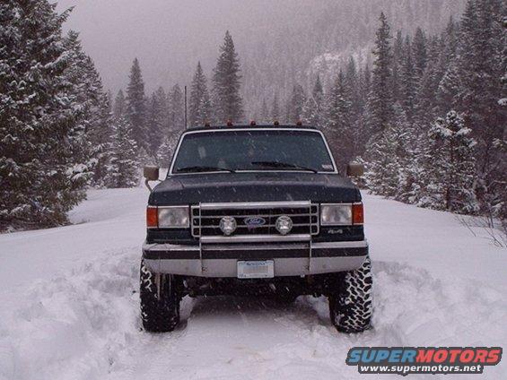 Ford F-Series truck in snow, front view. It has a chrome grille with fog lights and 4x4 badging