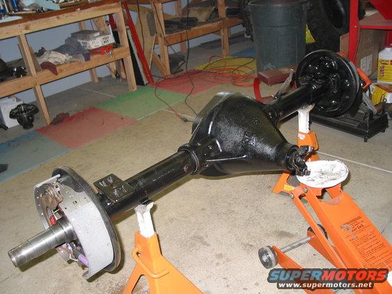 Black rear axle assembly on orange jack stands, showing brake drum and differential housing