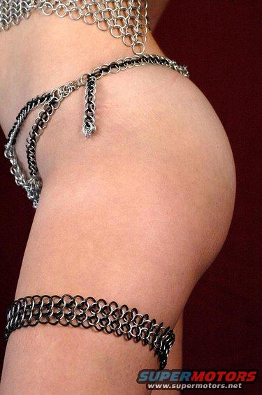 Chainmail adorns a human hip and thigh, with a black and silver chain belt and leg band