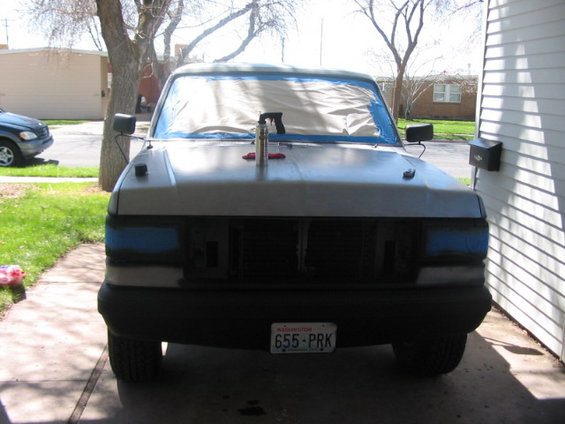 White Ford truck with blue tape on headlights, parked in a driveway