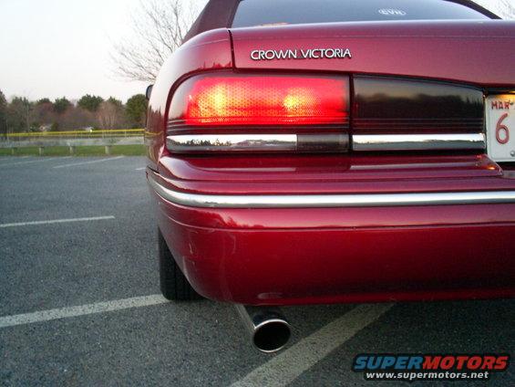 1995 Ford Crown Victoria rear bumper and taillight, red paint, chrome trim, exhaust pipe visible