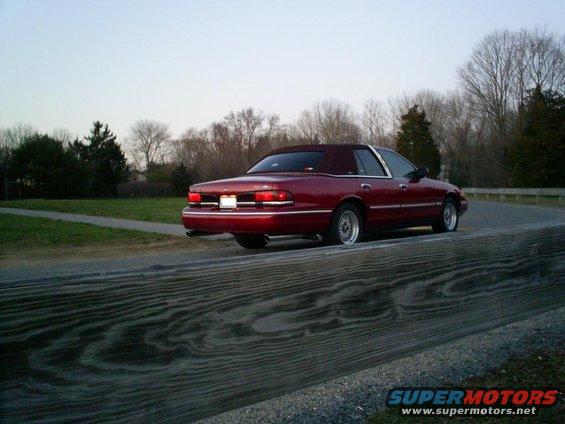 Red sedan with a vinyl top driving on a road