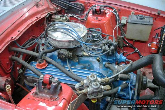 engine bay with blue valve covers, chrome air cleaner, and red fender wells. Some hoses and wires are visible