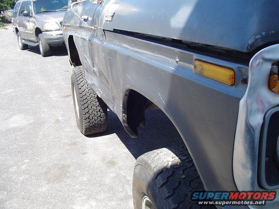 Side view of a 1979 Ford Bronco with aftermarket wheels and tires, parked behind another SUV