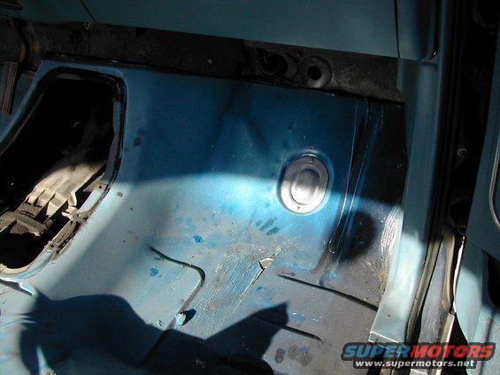 Blue interior floor with a circular metal insert and a dark opening on the left