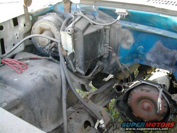 Engine bay with HVAC unit, fan motor, and transmission torque converter visible