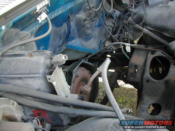 Close-up of a vehicle's engine bay, showing hoses, engine parts, and the firewall