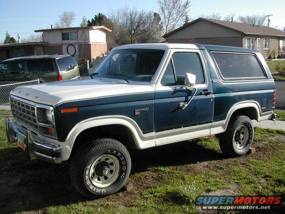 Dark teal and white Ford Bronco parked on grass