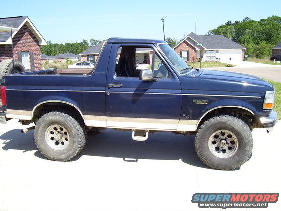 Side view of a blue 1992 Ford Bronco with tan lower body trim and aftermarket wheels