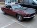 1969 Ford Mustang - A maroon 1969 Ford Mustang is parked on a concrete surface next to a white van and a black pickup truck.