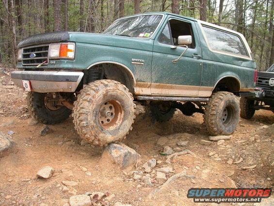 Green 1990 Ford Bronco navigating rocky terrain