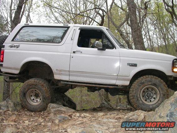 White Ford Bronco on rocks, 4x4 sticker on rear quarter panel, 'BRONCO' badge on fender