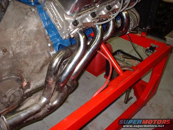 engine block with chrome headers and blue valve covers on a red stand