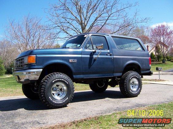 Blue Ford Bronco parked on a driveway, lifted with off-road tires
