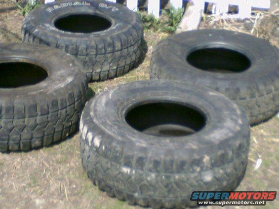 Four off-road tires with visible tread patterns and sidewall text