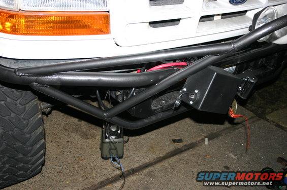 Ford truck front end with custom tube bumper, winch, and aftermarket lights. The grille has a Ford logo