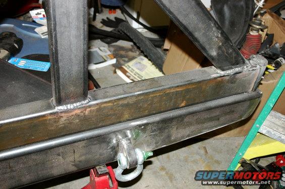 Steel frame section with welded joints and a tow hitch attachment, resting on a red jack