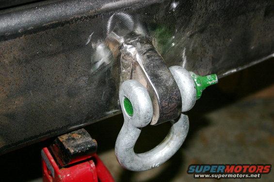 Close-up of a welded tow hitch shackle mount with a green-capped pin