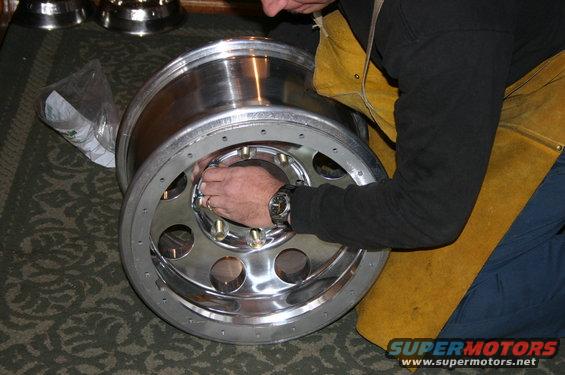 Chrome wheel being worked on by a person wearing a yellow apron