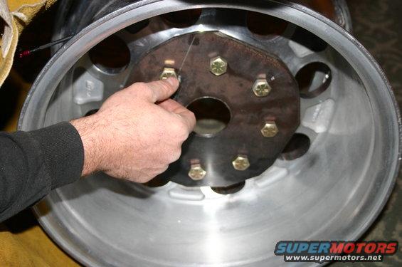 hand attaching adapter plate to a wheel rim with bolts