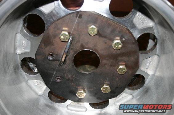 Close-up of a metal wheel hub with six bolts and a central circular opening