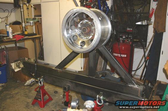 Metal tire carrier and bumper assembly with a chrome wheel mounted on a stand