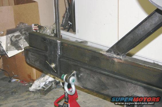 Custom fabricated steel bumper section with welded brackets and a tow shackle mount, supported by a red jack stand