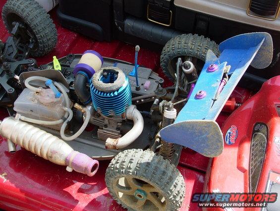 Remote control car engine with blue fins and purple air filter, on a red surface