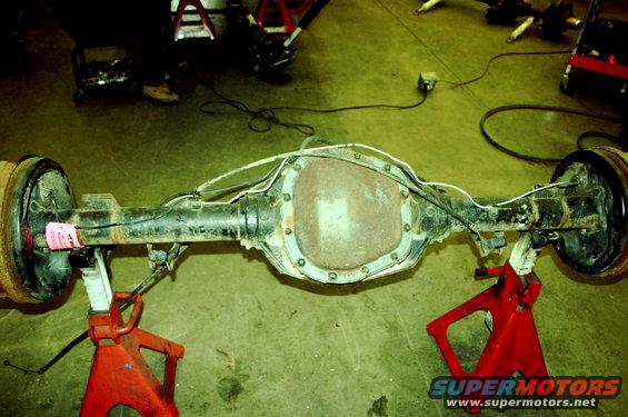 Rear axle assembly on jack stands with pink tag on brake drum