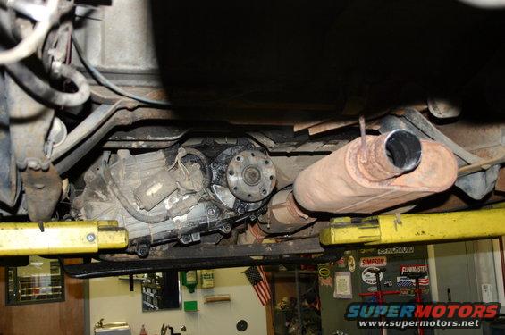 Underside of a vehicle on a lift showing transmission, transfer case, and exhaust system