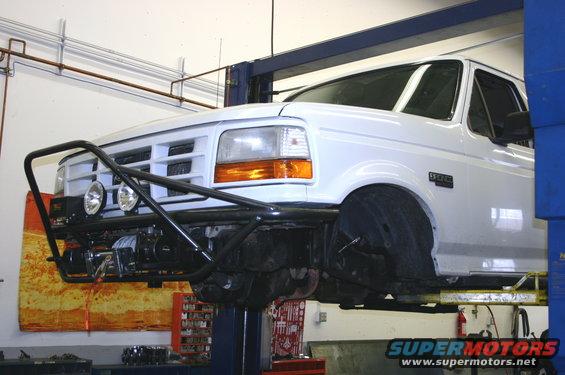 White 1995 Ford Bronco with brush guard and winch on lift