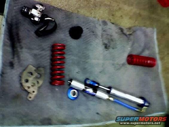 Coilover shock, red coil spring, and other suspension components on a gray cloth