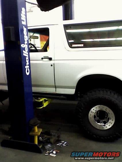 White SUV on a lift, side view. Challenger Lifts logo visible on the lift