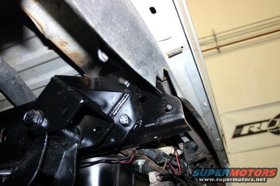 Black painted suspension bracket with bolts and wiring underneath