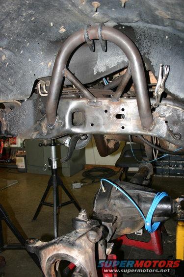 Custom suspension modification with a U-shaped hoop and bracing welded to a vehicle frame. Differential and suspension components are visible below